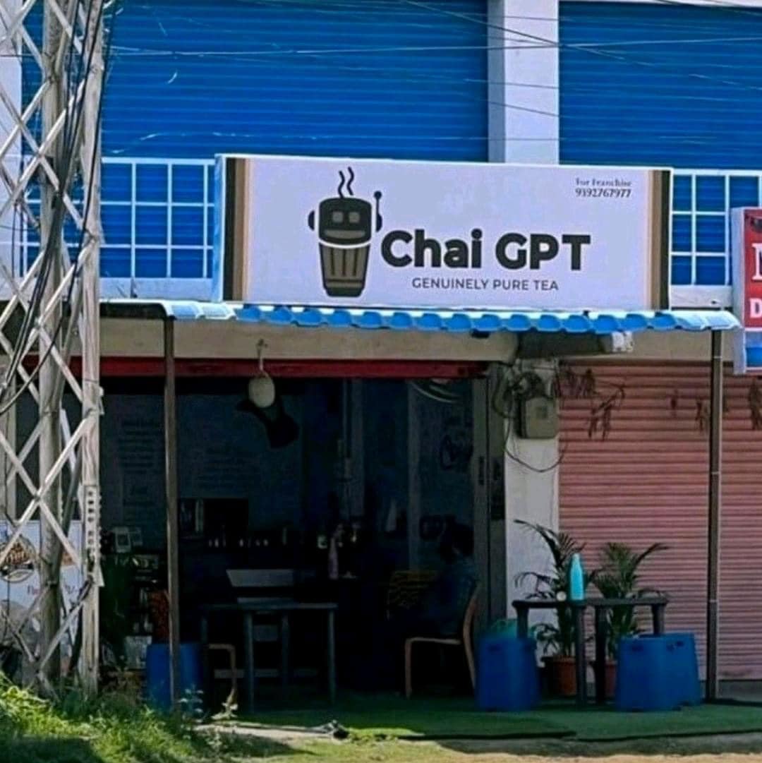 This meme is a play on the popular AI chatbot, GPT. The image is of a storefront with a sign that reads "Chai GPT" and features a robot holding a cup of chai. The text "Genuinely Pure Tea" is written below the sign, poking fun at the idea that the tea shop is named after a language model.